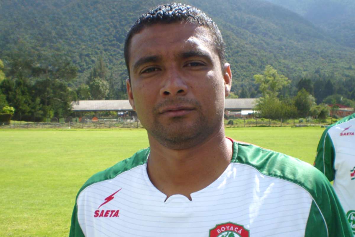 Hombre vestido con un uniforme de fútbol verde y blanco, posando en un campo deportivo.